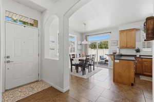 Entryway featuring a transom window, leading to a dining area with sliding glass doors to the patio, kitchen with wood cabinetry, and tile flooring throughout