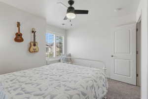 Bedroom featuring a window with plantation shutters, a black ceiling fan with integrated lighting, a white paneled interior door, and gray carpet flooring