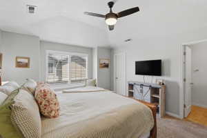 Vaulted ceiling bedroom featuring a ceiling fan with integrated lighting, window with white louvered shutters, and light-toned carpeting