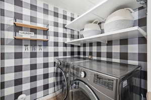 Laundry area featuring black and white buffalo check wall treatment, white ceiling with wood-finish planks, and durable wood-look flooring