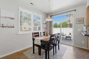 Dining area featuring white plantation shutters, a modern pendant light fixture, and tile flooring