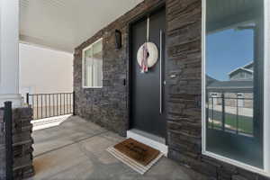 Covered front porch featuring a dark stacked stone facade
