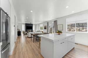 Bright open-concept living space featuring wood-finish flooring, recessed lighting, and white walls