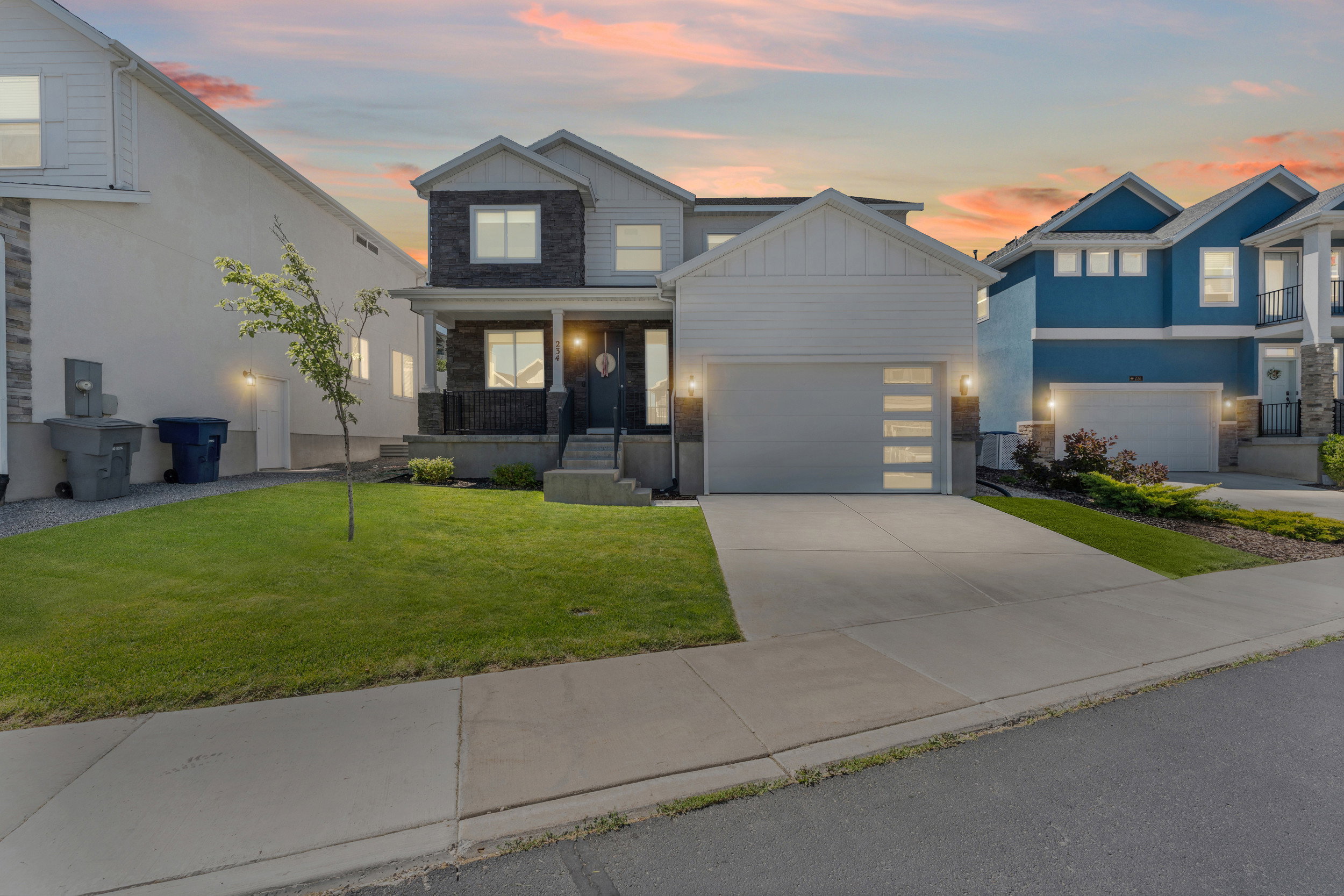 Contemporary two-story residence featuring a striking combination of white siding and dark stone veneer accents