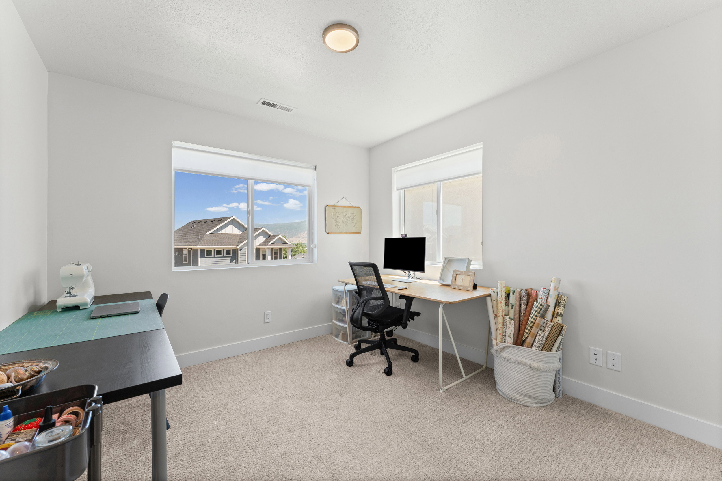 Spacious room featuring neutral carpeting, light-colored walls, and two large windows with white blinds