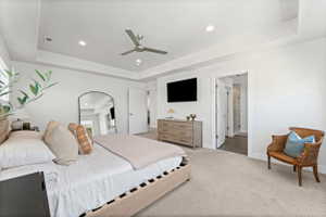 Bedroom featuring tray ceiling with recessed lighting, ceiling fan, and neutral carpet flooring