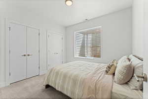 Room featuring neutral wall tones, carpet flooring, a window with plantation shutters, a flush-mount ceiling light, and two bifold closet doors