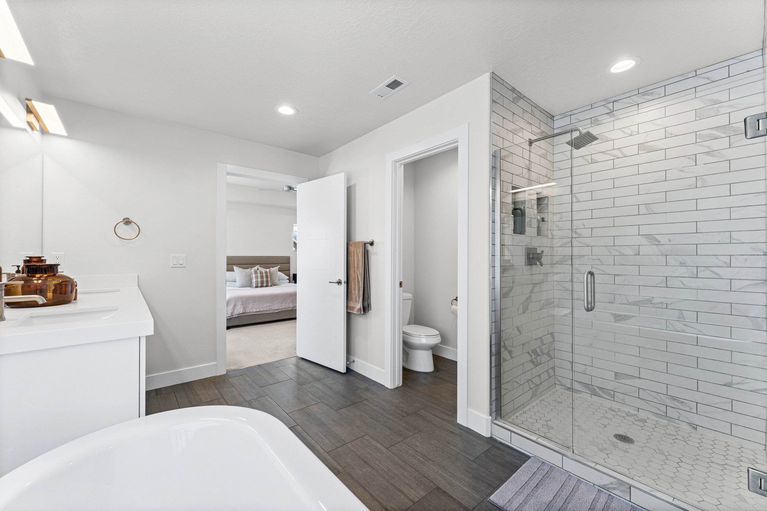 Walk-in shower with clear glass enclosure and white subway tile surround, featuring a rainfall showerhead