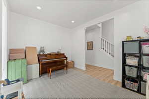 Versatile room featuring light-toned walls, recessed lighting, and a combination of wood-finish flooring and patterned carpeting