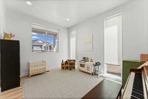 Spacious room featuring light-toned walls, recessed lighting, and wood-finish flooring