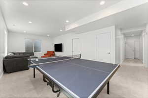 Versatile recreation area featuring recessed lighting, light-toned carpeting, and a window with horizontal blinds