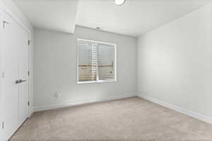 Carpeted interior space featuring white walls and a large window with blinds