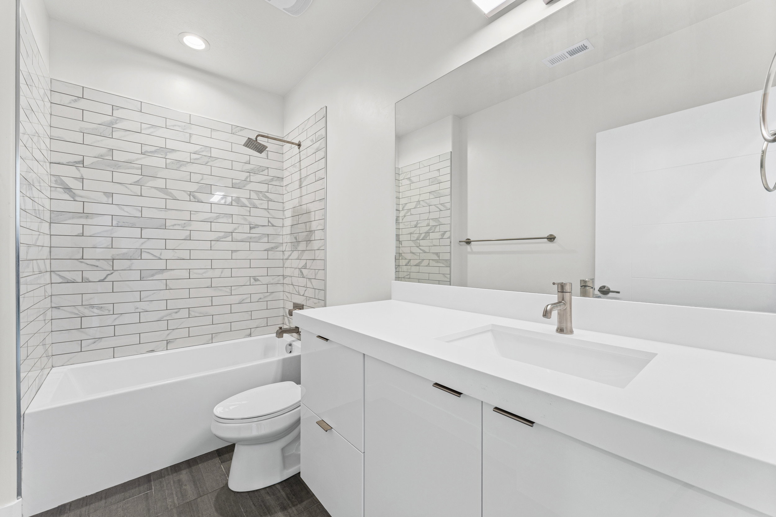 Modern bathroom featuring a vanity with an integrated sink, brushed nickel faucet, and full-width mirror