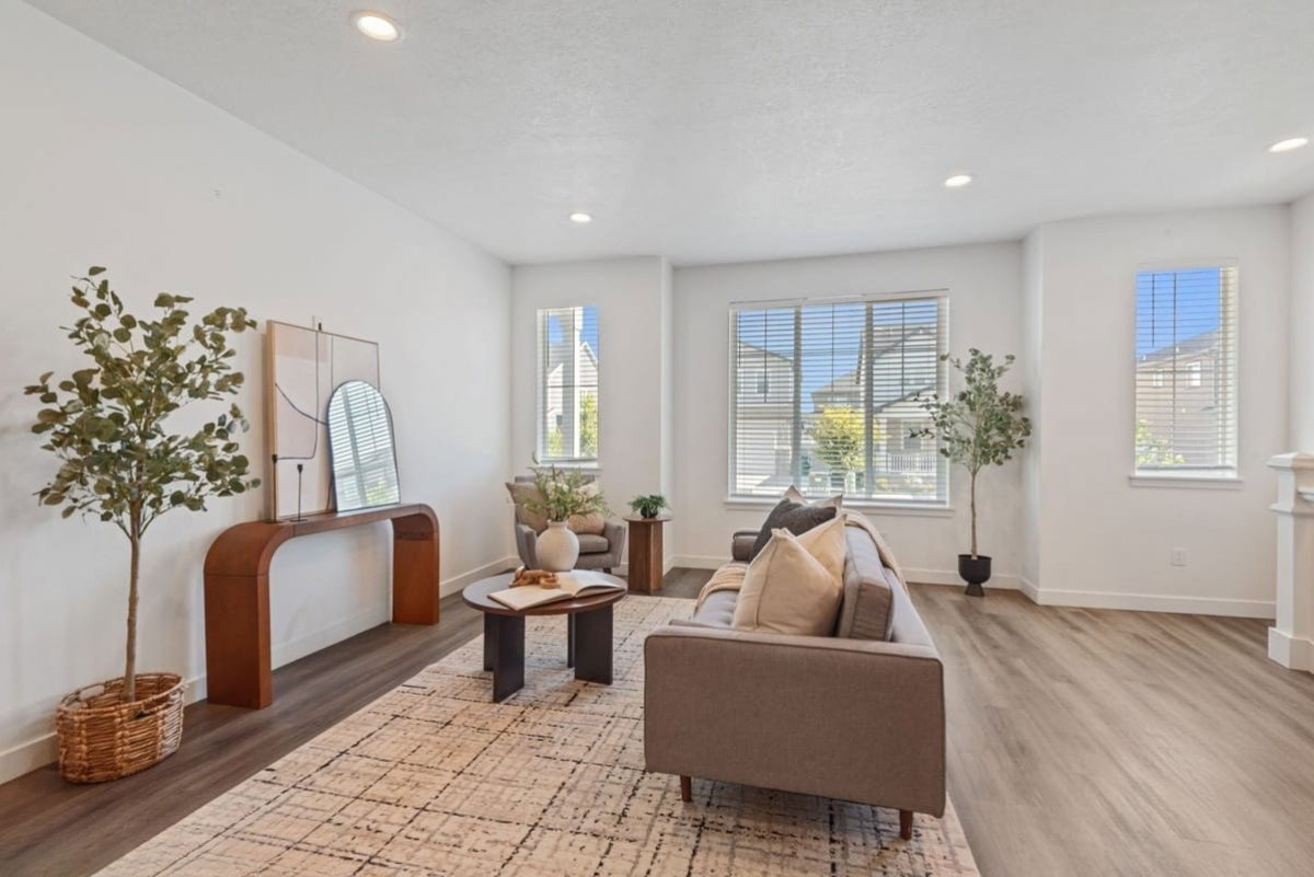 Spacious living area featuring light wood-finish flooring, recessed lighting, and ample natural light from multiple windows