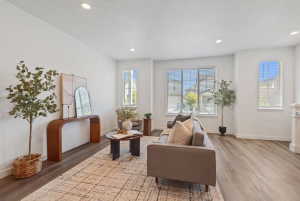Spacious living area featuring light wood-finish flooring, recessed lighting, and ample natural light from multiple windows