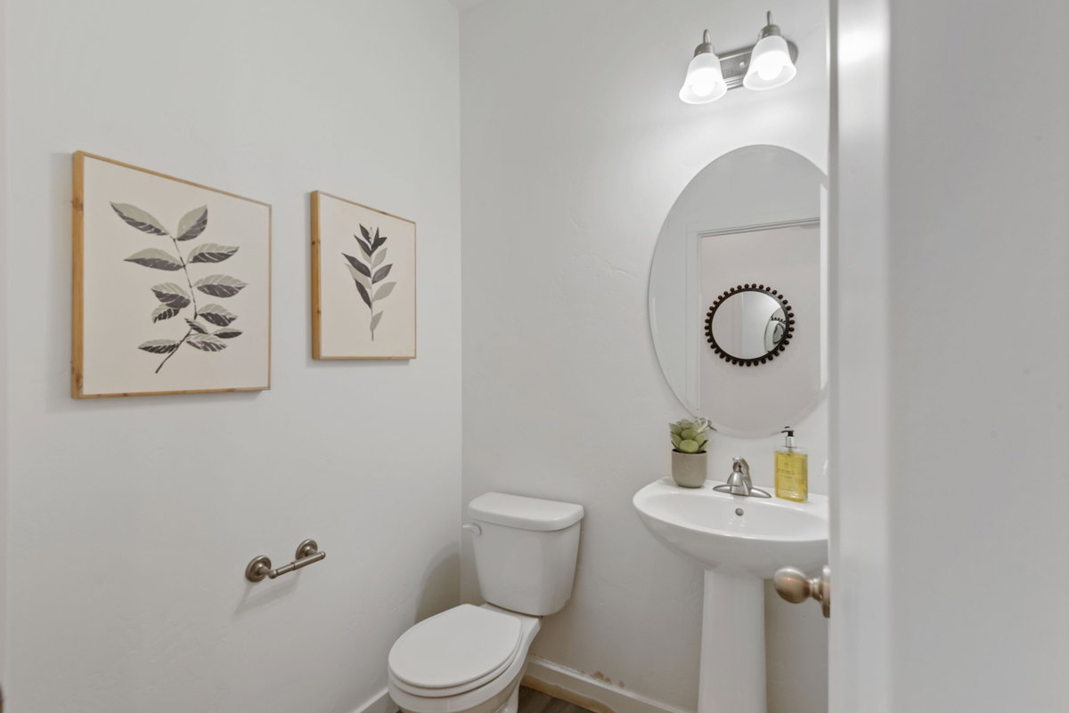 Bathroom featuring a pedestal sink with a single-handle faucet, oval mirror, and a two-bulb vanity light fixture