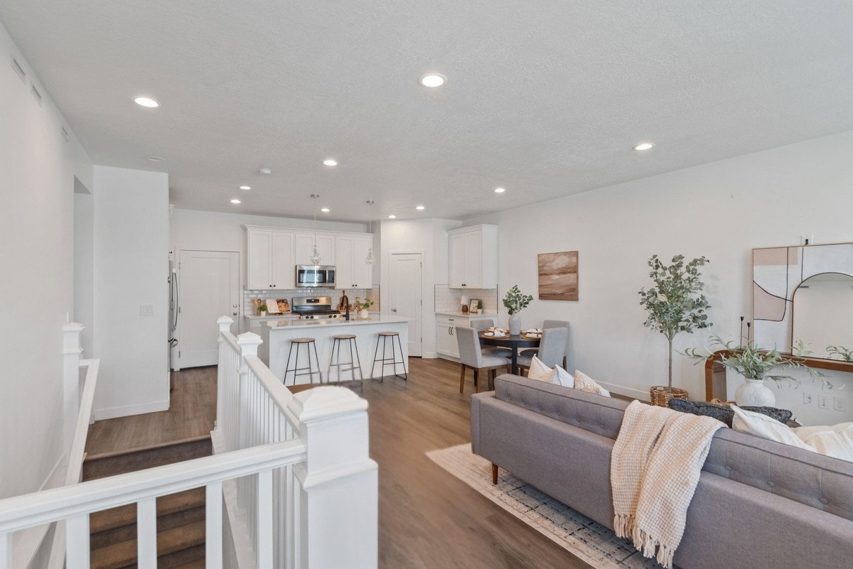Open-concept living area featuring wood-finish flooring, recessed lighting, and a white baluster staircase