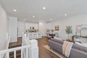 Open-concept living area featuring wood-finish flooring, recessed lighting, and a white baluster staircase