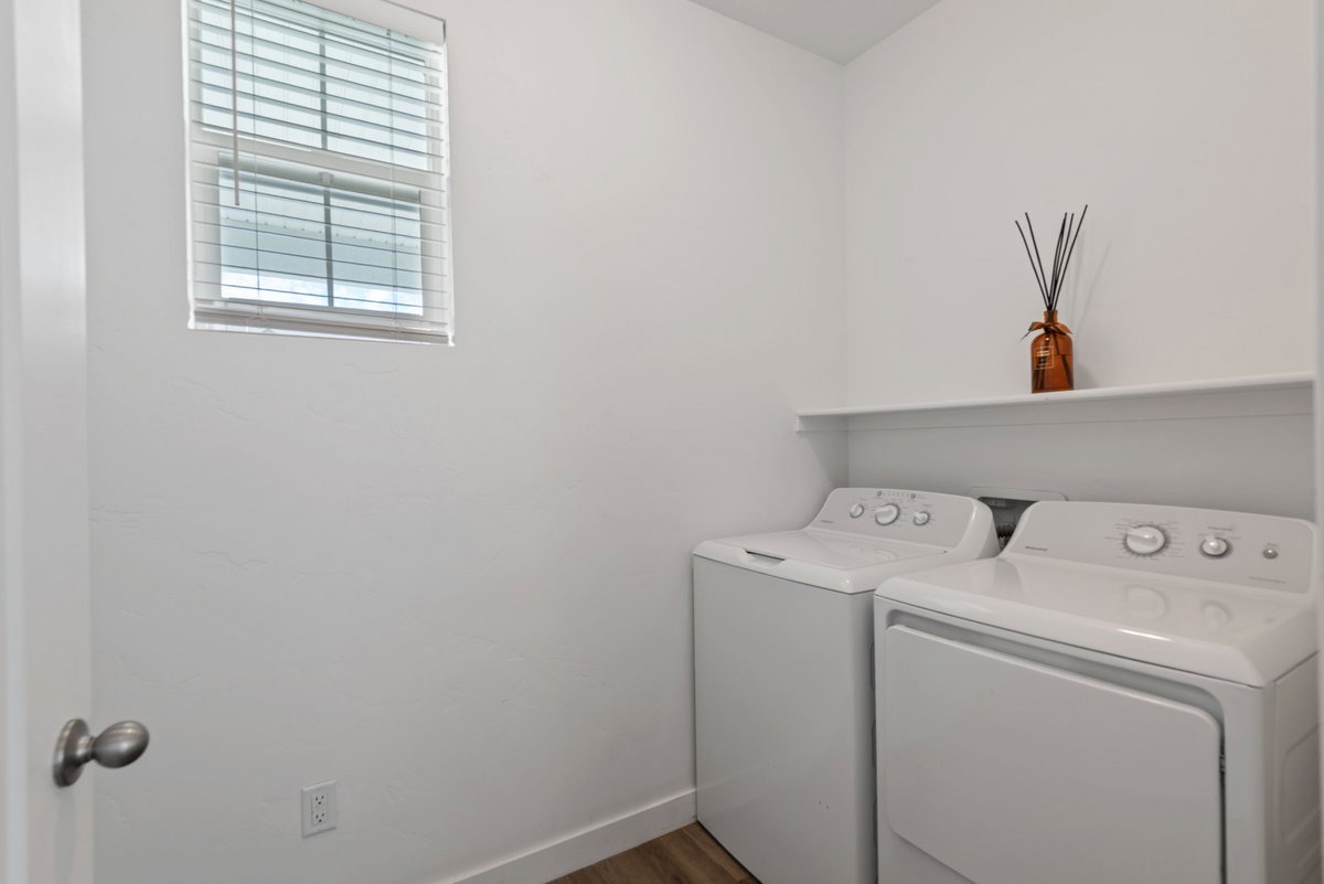 Dedicated laundry area featuring a window with blinds, a built-in shelf, and wood-finish flooring