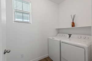 Dedicated laundry area featuring a window with blinds, a built-in shelf, and wood-finish flooring