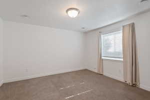 Carpeted room featuring a single window with blinds and drapes, a flush-mount ceiling light fixture, and white baseboards