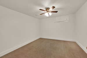Carpeted room featuring a ceiling fan with integrated lighting, white walls, and clean white baseboards
