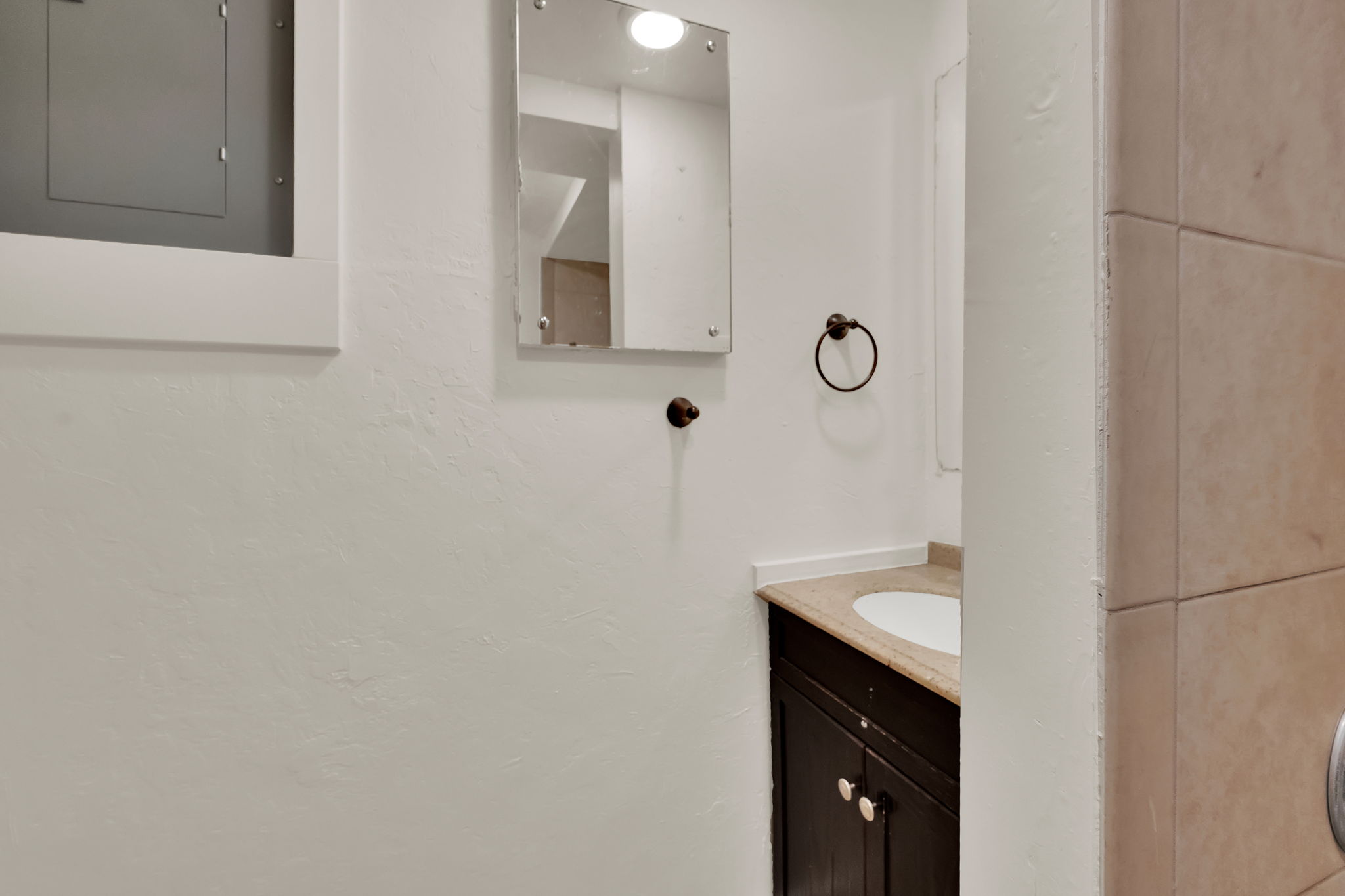 Compact vanity with a built-in sink, stone-finish countertop, and dark wood-finish cabinetry
