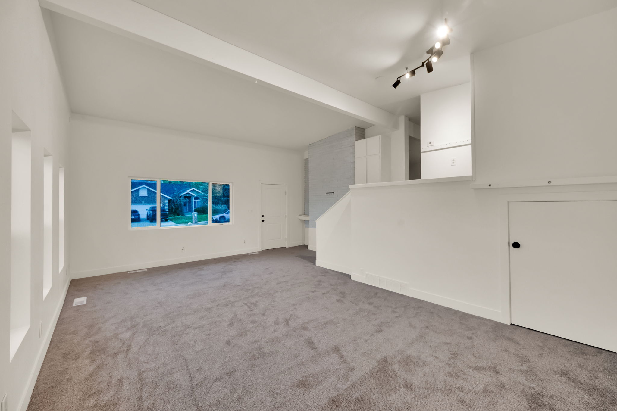 Spacious living area featuring neutral carpeting and white painted walls