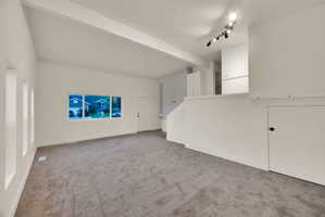 Spacious living area featuring neutral carpeting and white painted walls