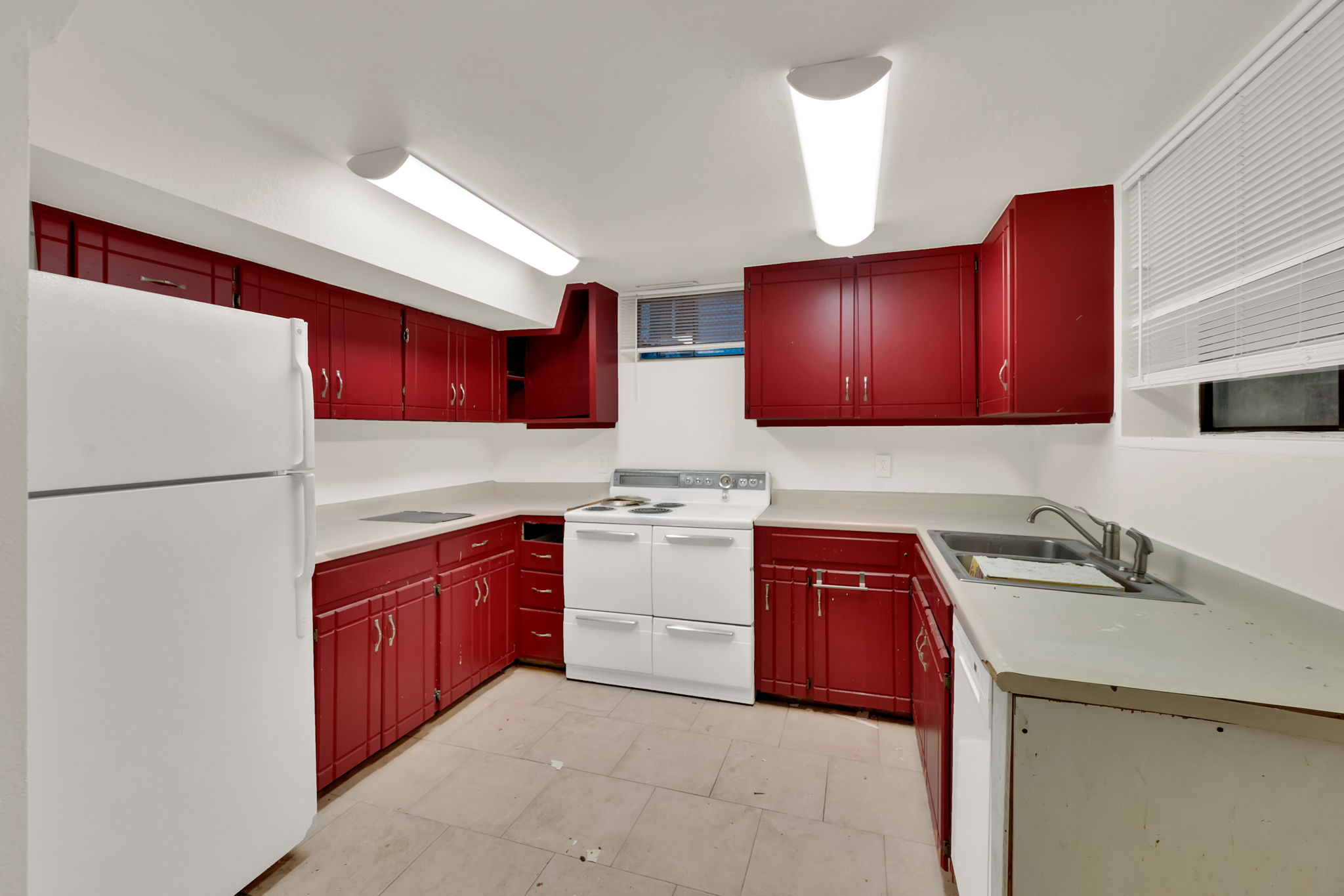 Kitchen featuring red cabinetry, white countertops, white appliances, and a stainless steel sink