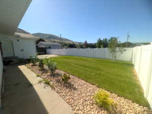 Expansive backyard featuring a lush lawn, white vinyl fencing, and a decorative rock border with plantings