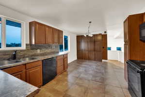 Kitchen featuring wood-finish cabinetry, a double basin stainless steel sink with a matte black faucet, and a stone-tile backsplash