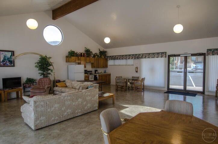 Vaulted ceilings with exposed wood beam, a circular window, and spherical pendant lighting