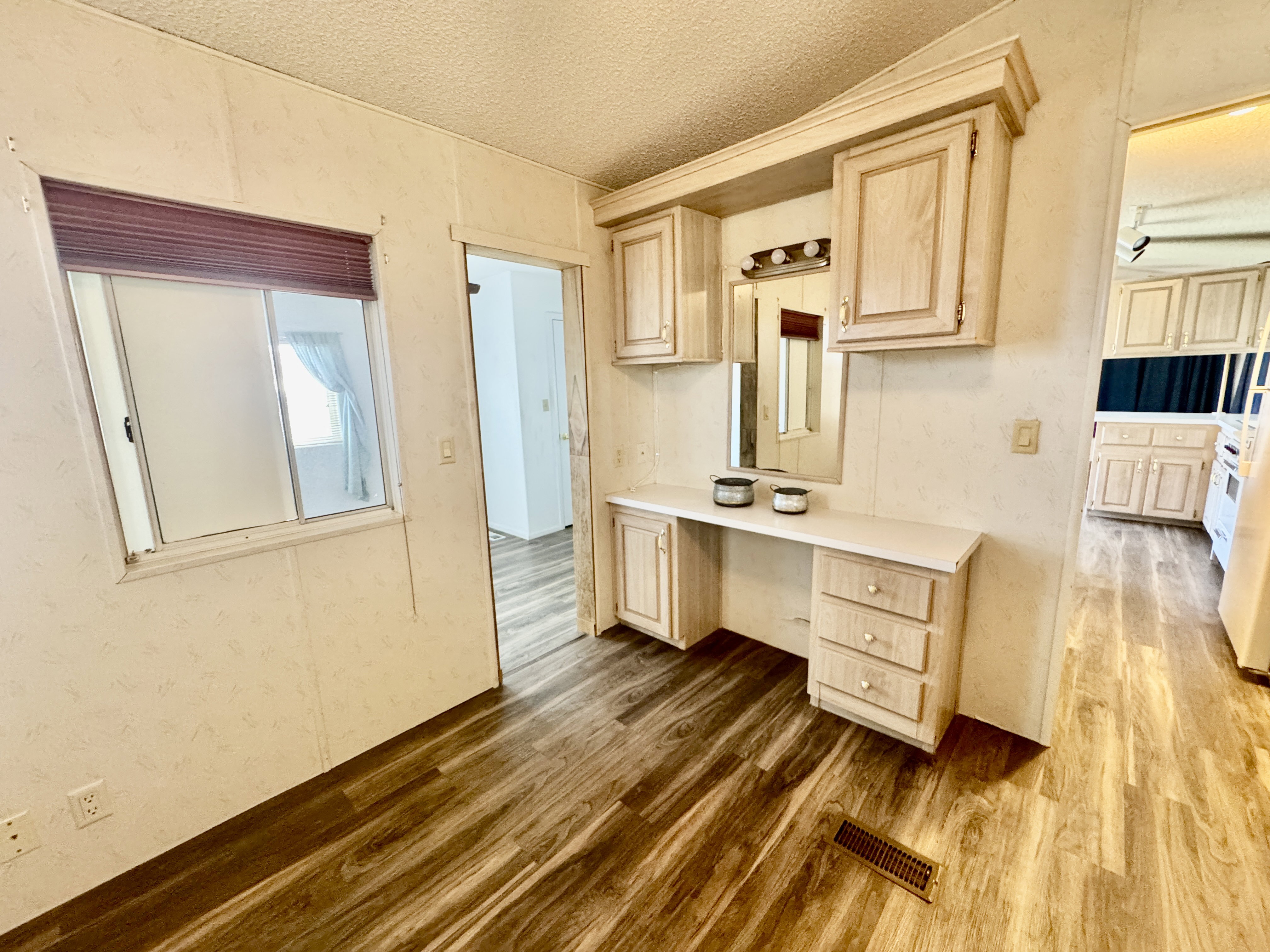 Integrated vanity with upper and lower cabinetry, wood-finish flooring, and a sliding window
