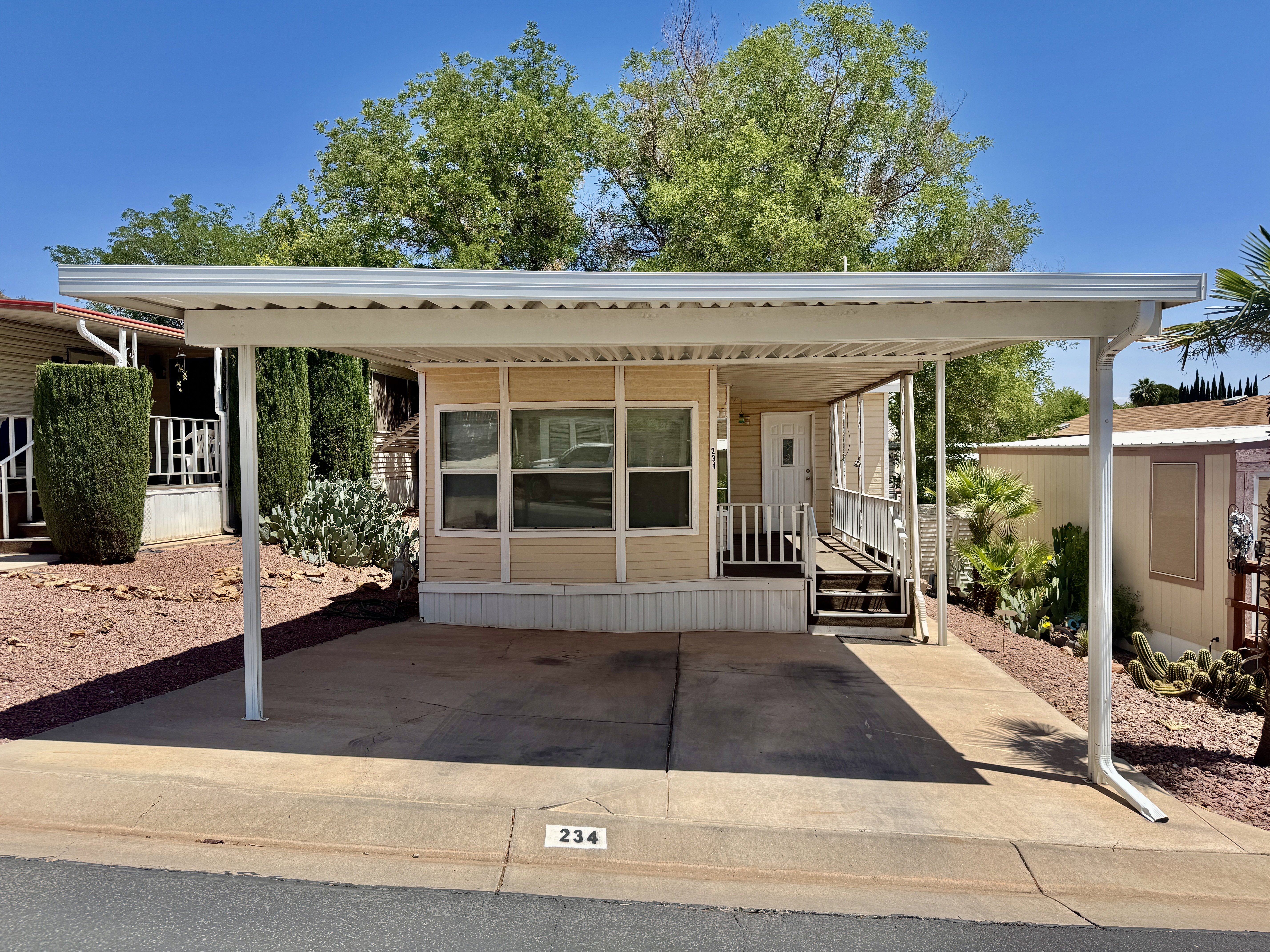 Property exterior featuring a covered carport, porch with railing, exterior siding, and a white entry door