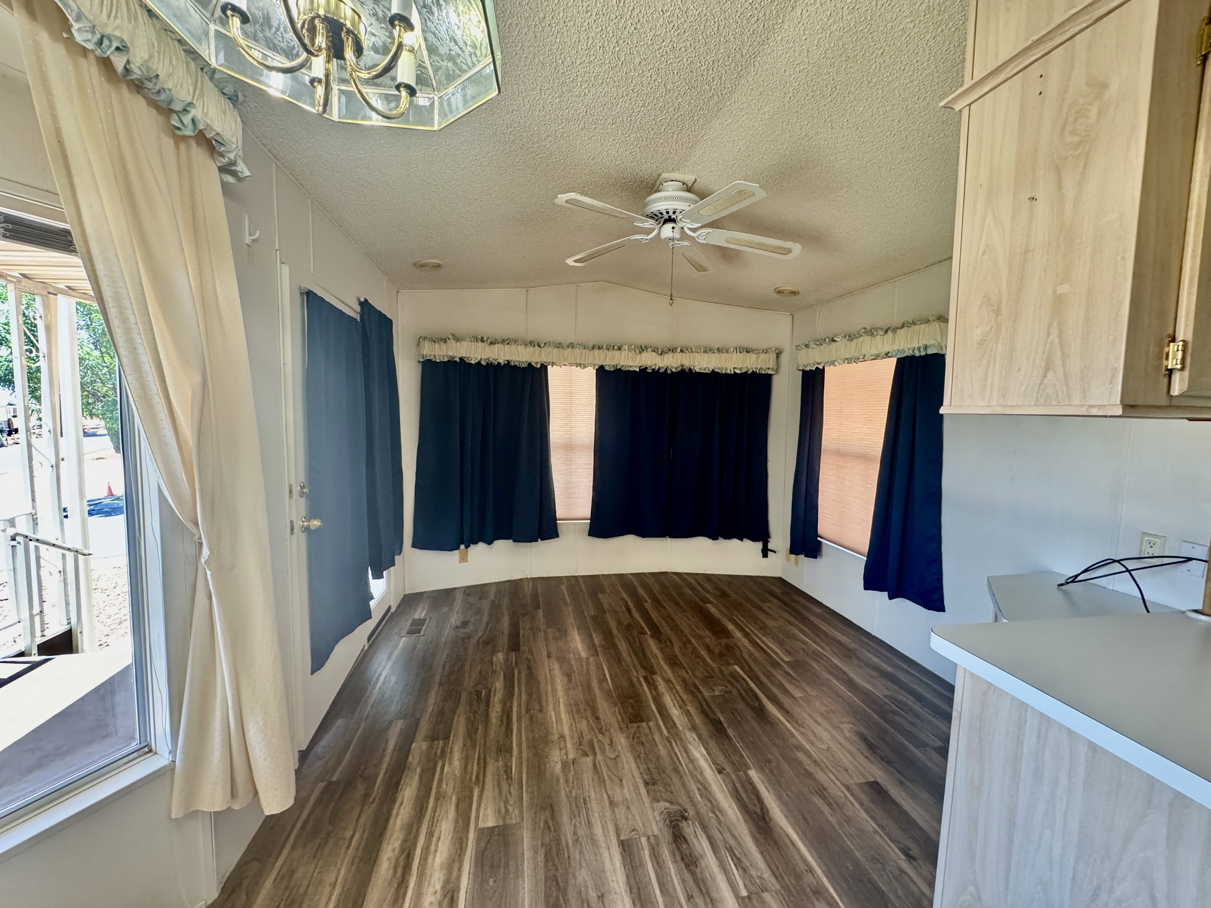 Spacious interior with wood-finish flooring, a multi-speed ceiling fan, and multiple windows