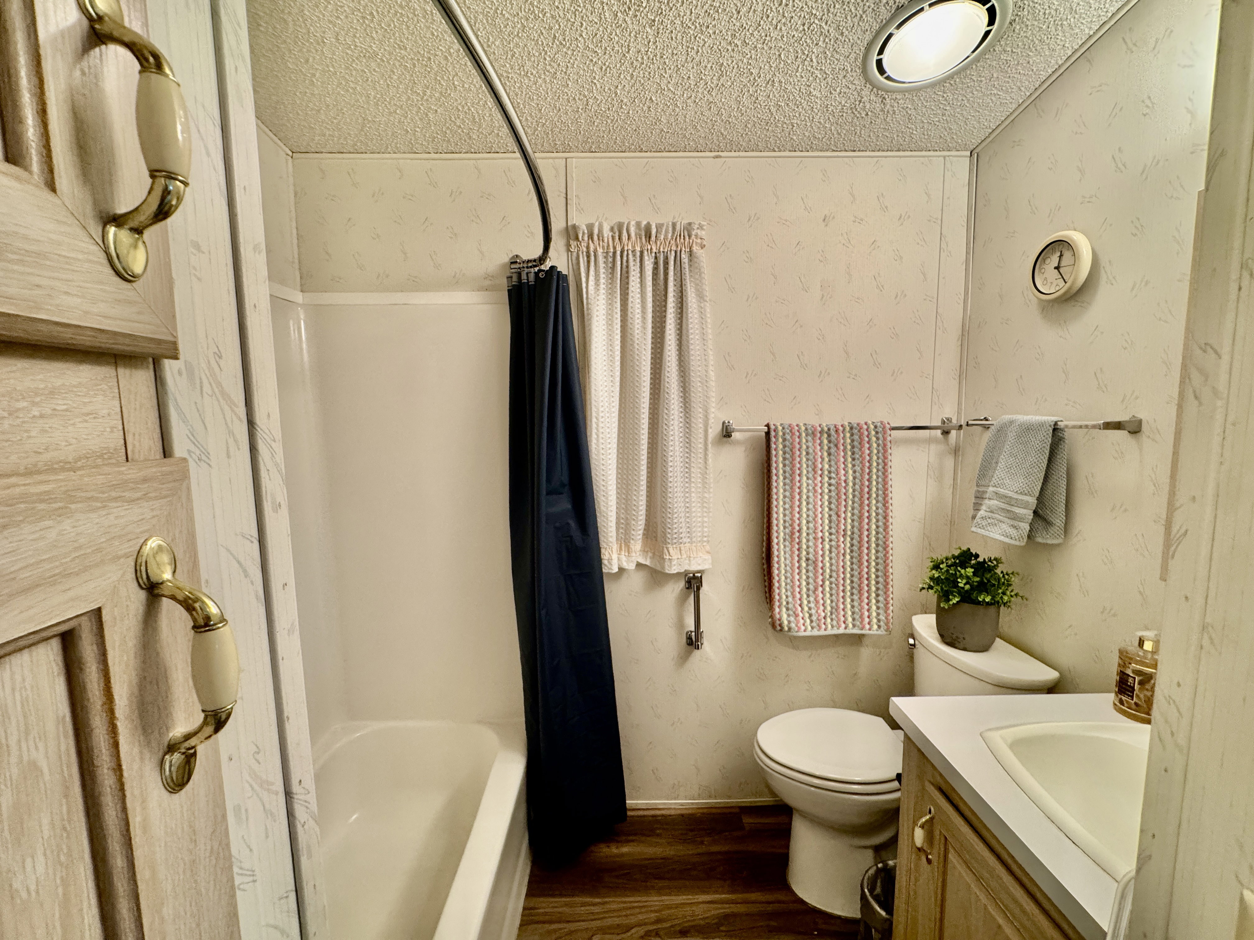 Bathroom featuring a white bathtub, wood-finish flooring, and a vanity with a white countertop and integrated sink