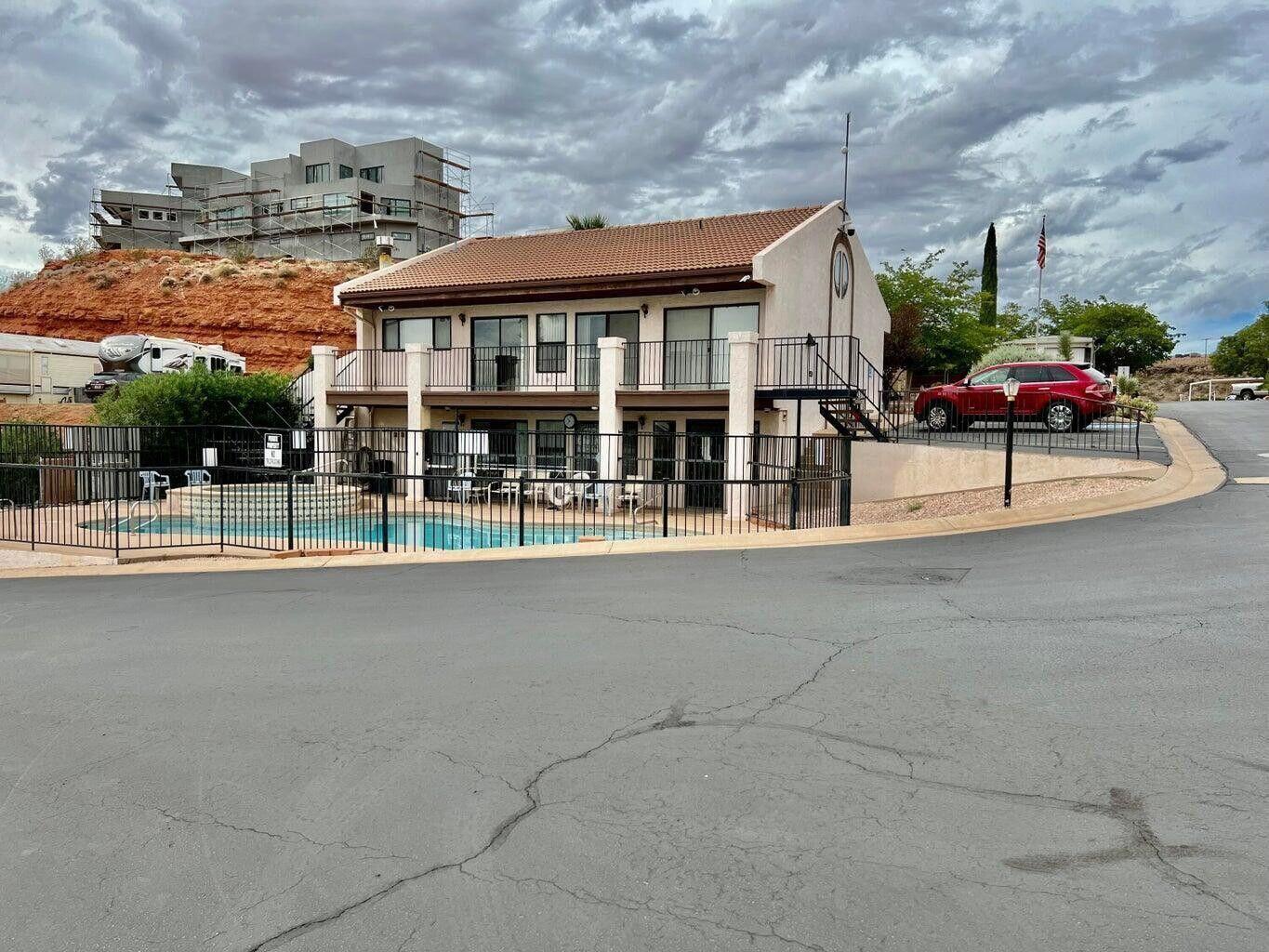 Two-story property with a tile roof and stucco exterior, featuring a black wrought iron fence enclosing an in-ground swimming pool