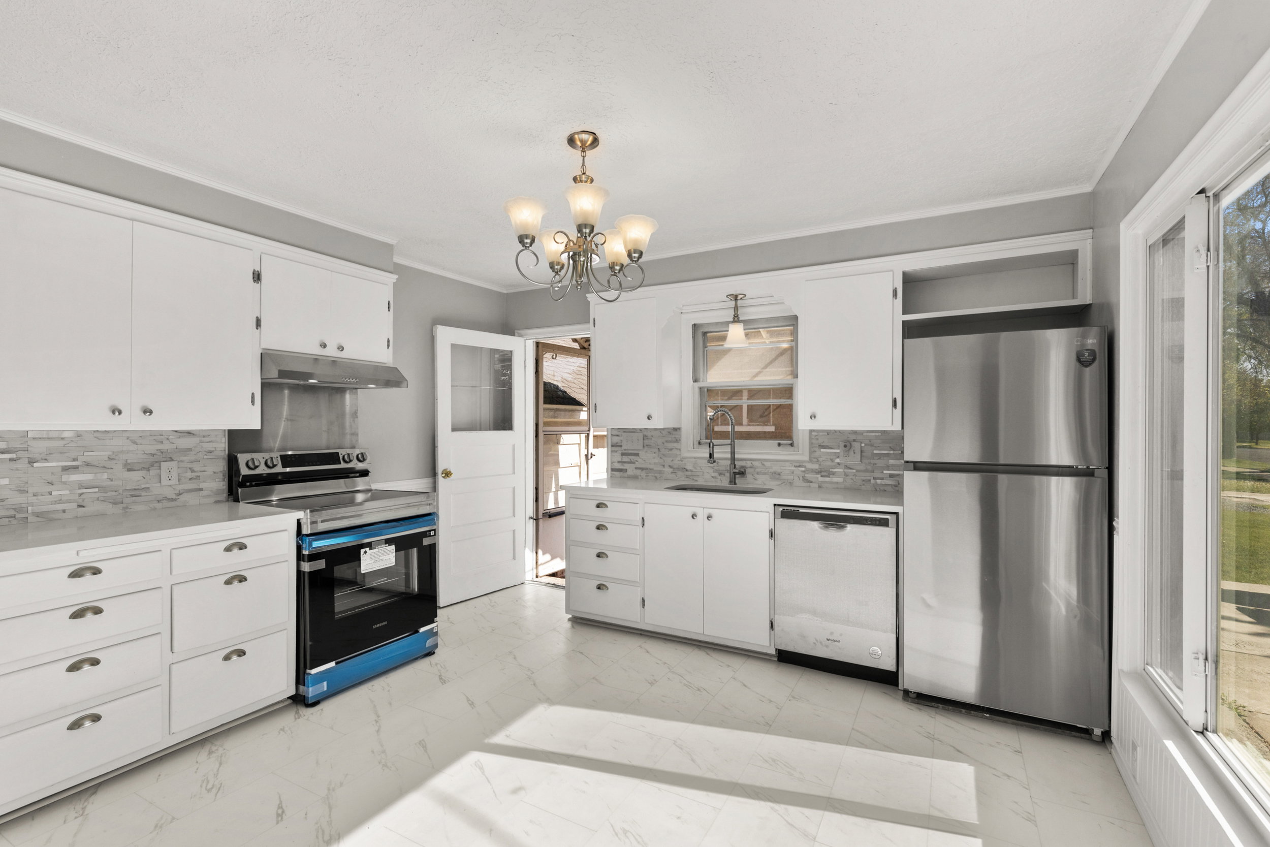 Kitchen featuring white cabinetry, light-toned countertops, and a mosaic tile backsplash