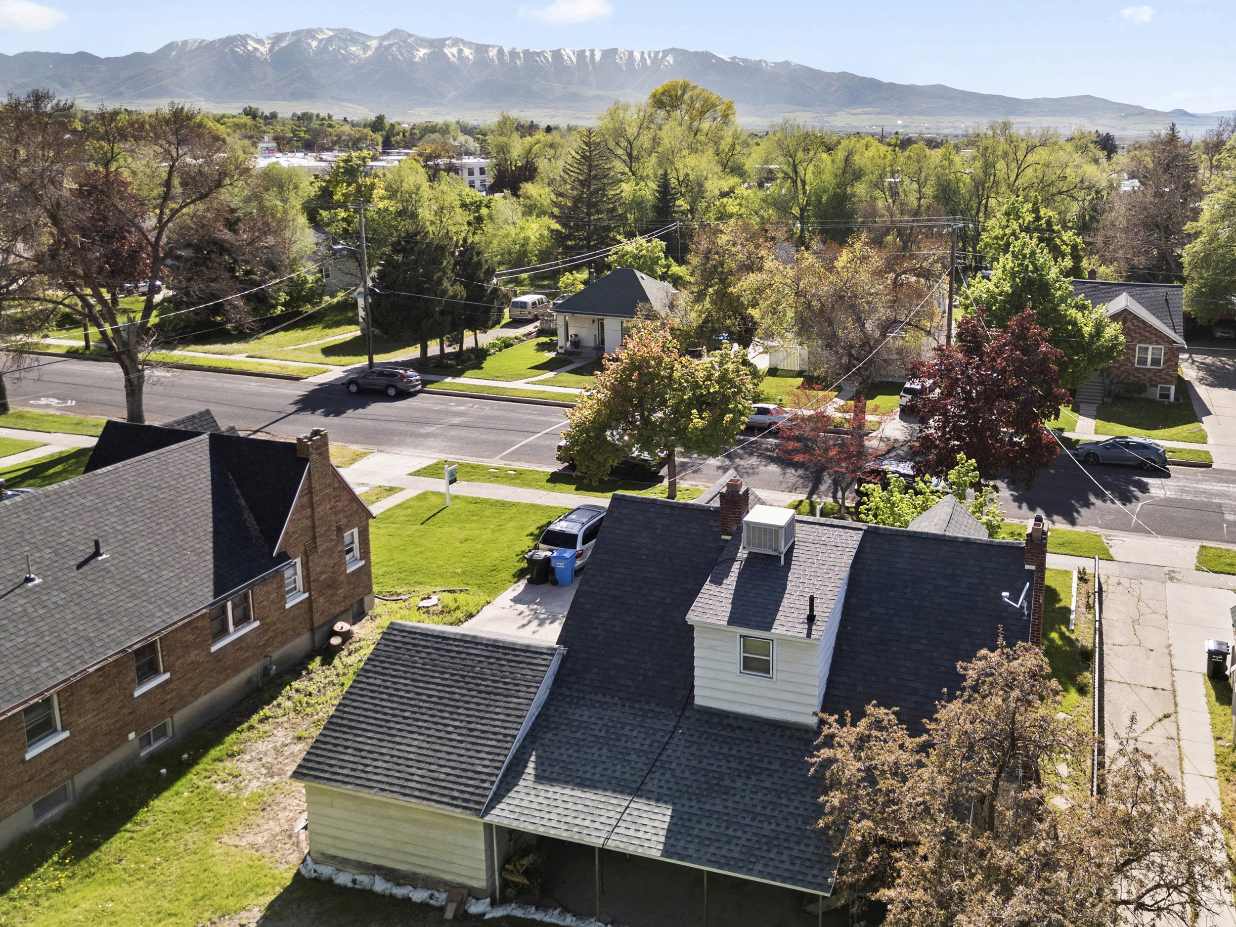 Gable roofline with dormer window and chimney, surrounded by mature trees and residential streets