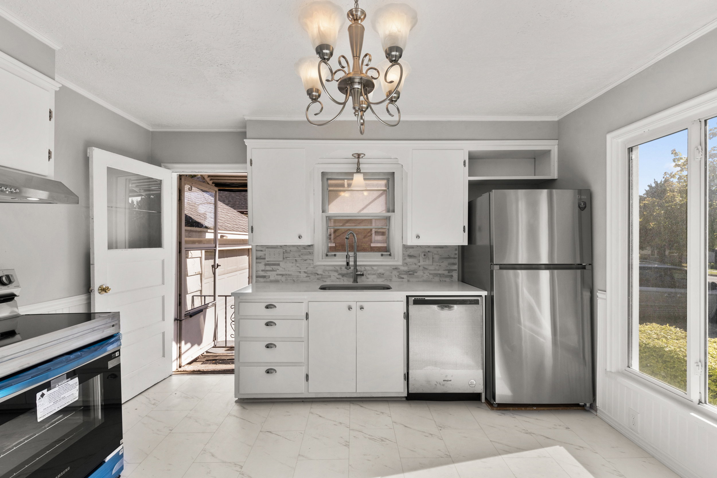 Kitchen featuring white cabinetry, stainless steel appliances, a tile backsplash, and tile flooring
