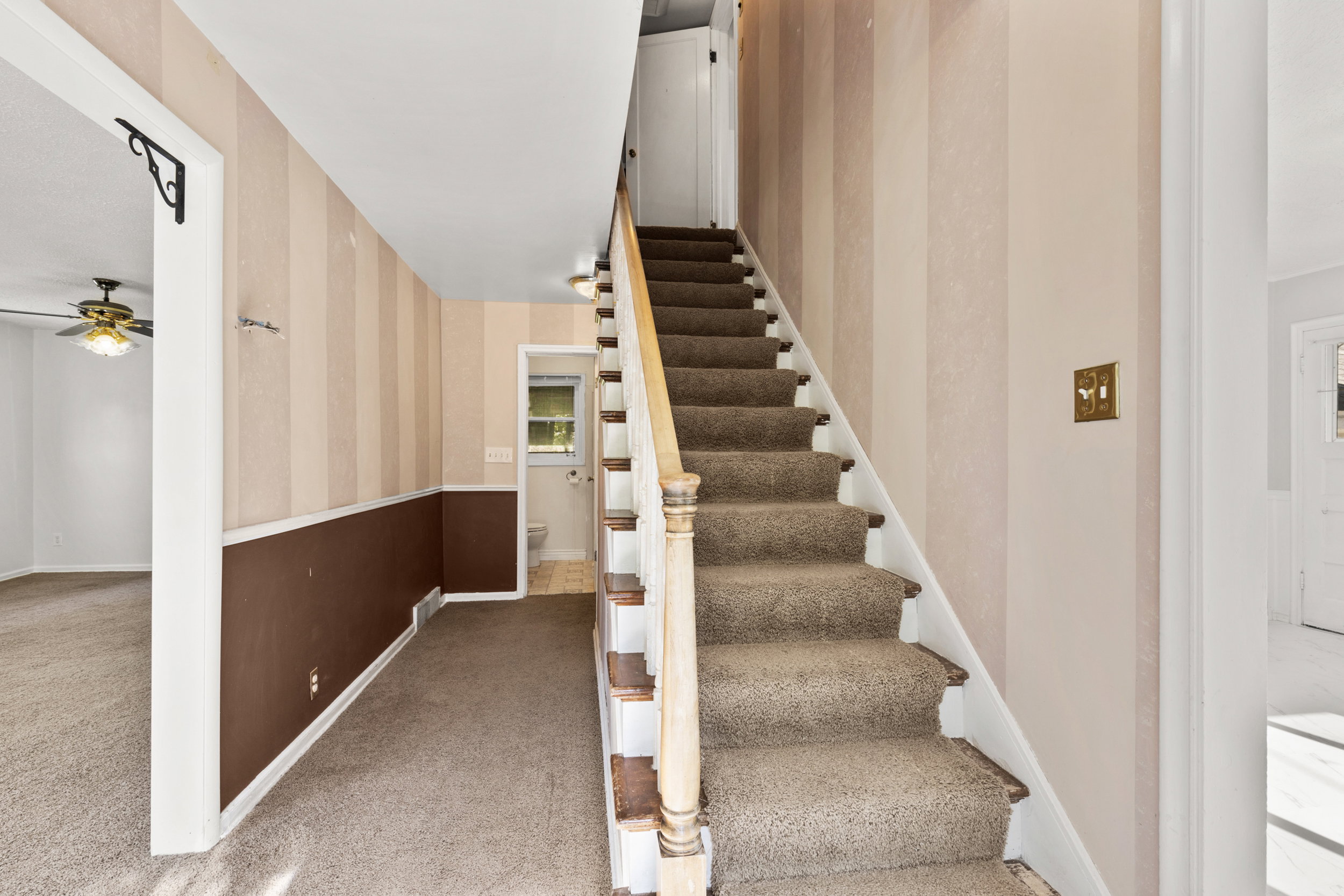 Carpeted staircase with wood-finish handrail and balusters