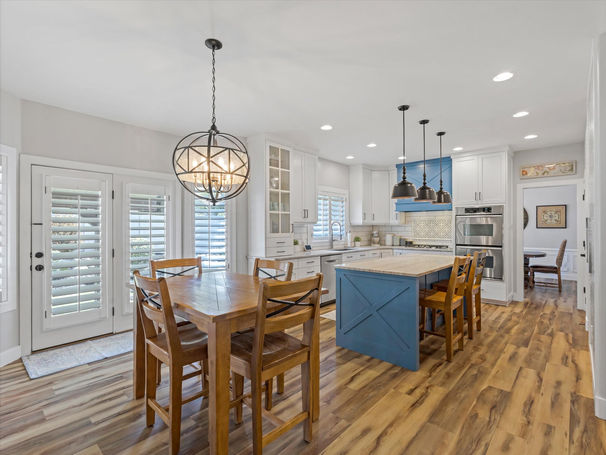 Spacious kitchen featuring wood-finish flooring, white cabinetry, and a central island with a contrasting blue base