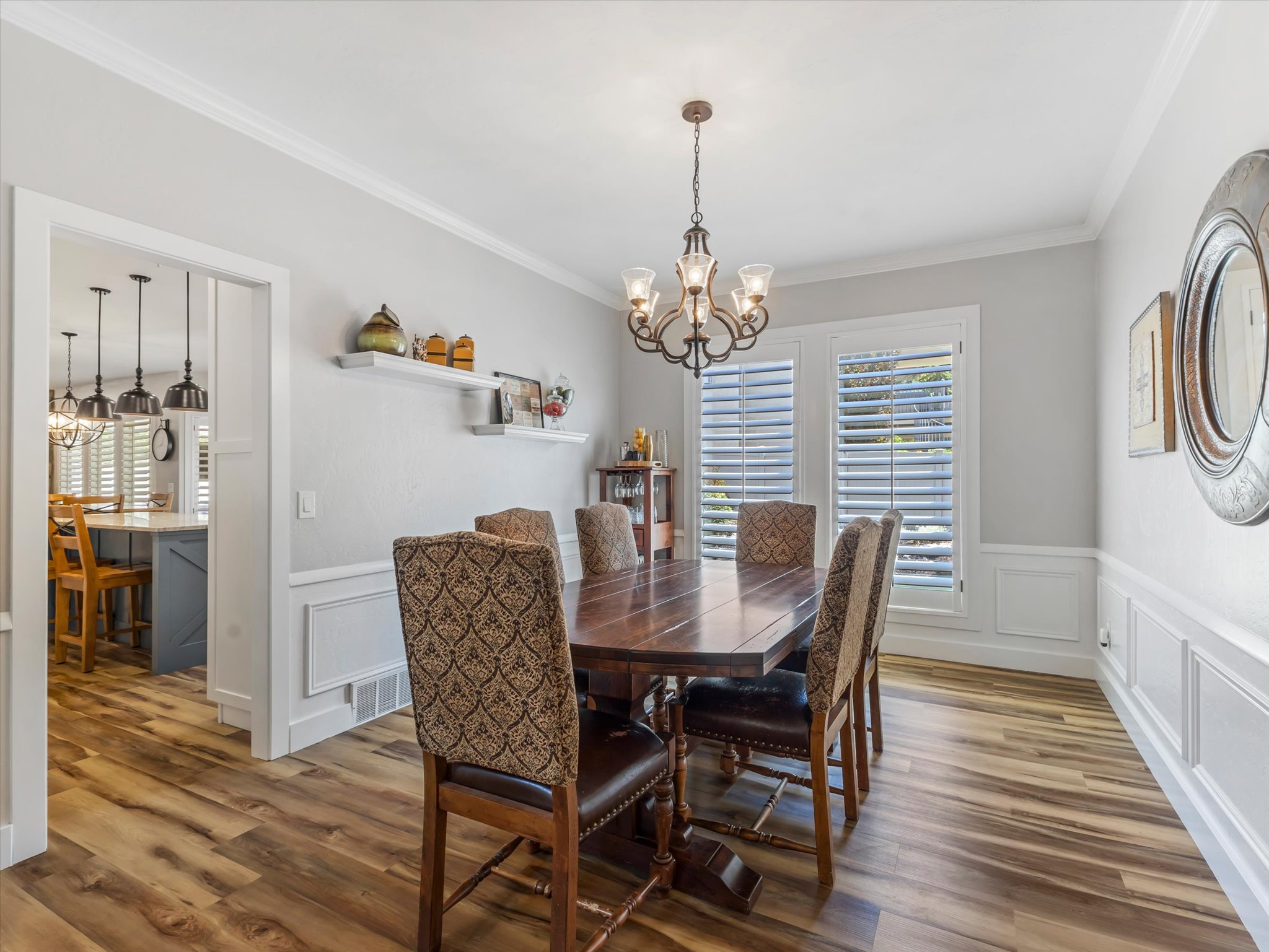 Formal dining area featuring wood-finish flooring, white wainscoting, and crown molding