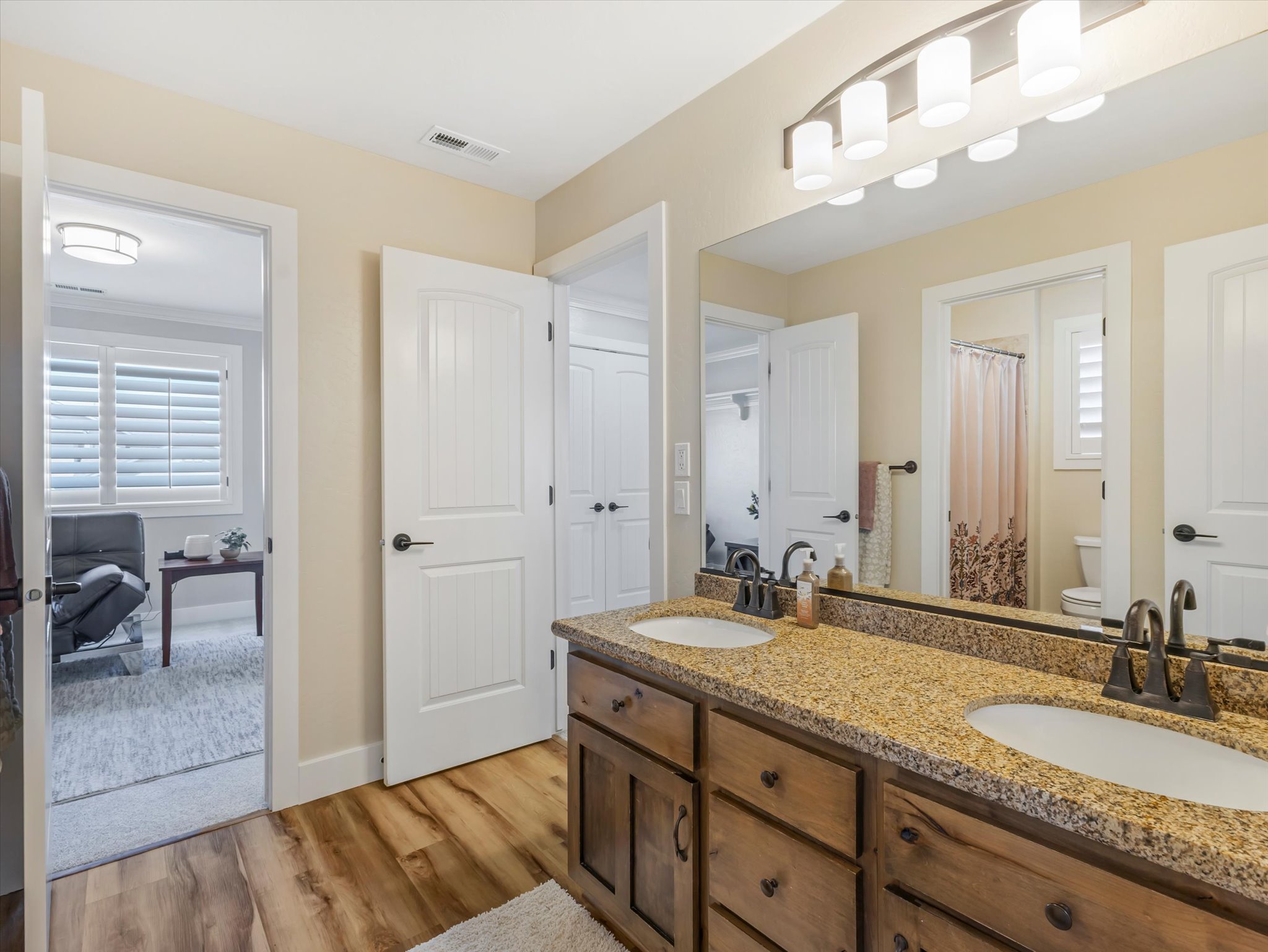 Bathroom featuring a double vanity with granite countertop and wood-finish cabinetry