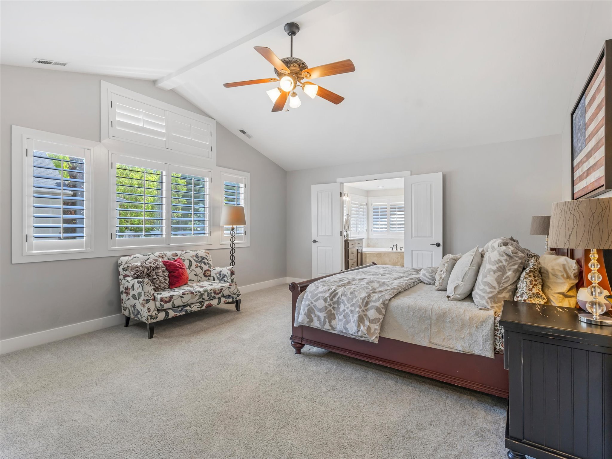 Vaulted ceiling with a ceiling fan, white window shutters, and light-toned carpet flooring