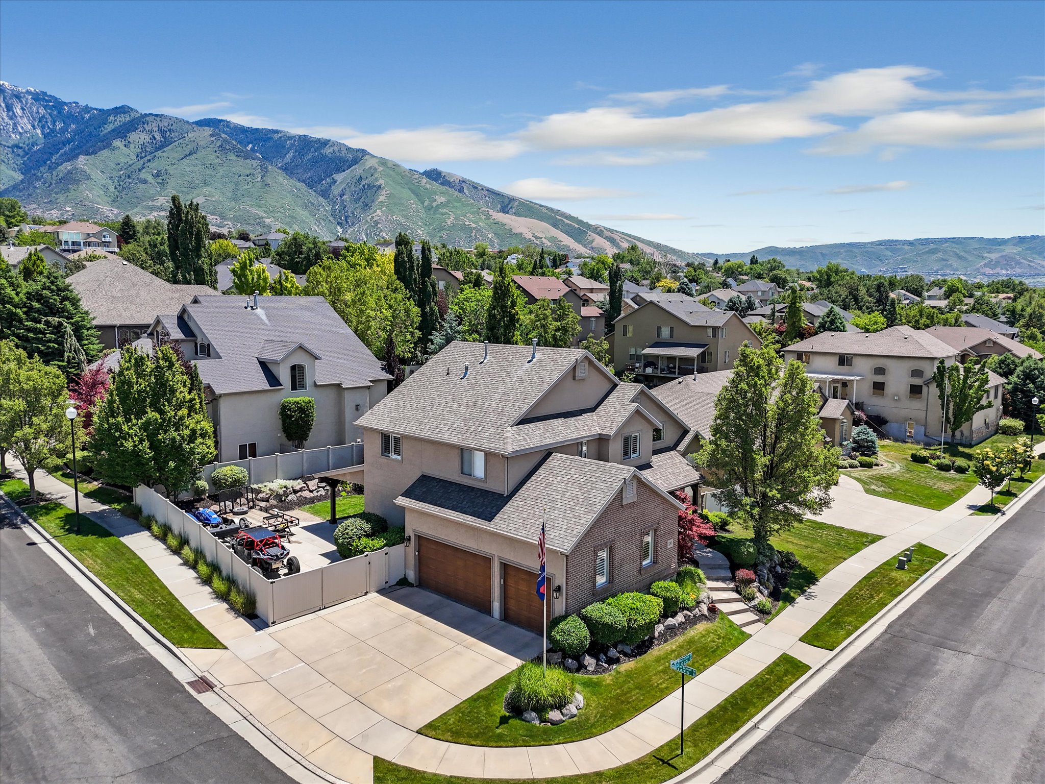 Two-story residence featuring a brick and stucco exterior, an attached two-car garage, and mature landscaping