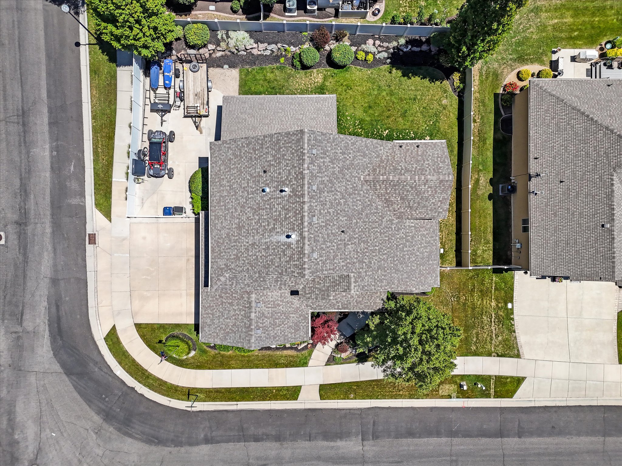 Expansive corner lot featuring a multi-gabled roofline and an attached garage with an extended concrete driveway