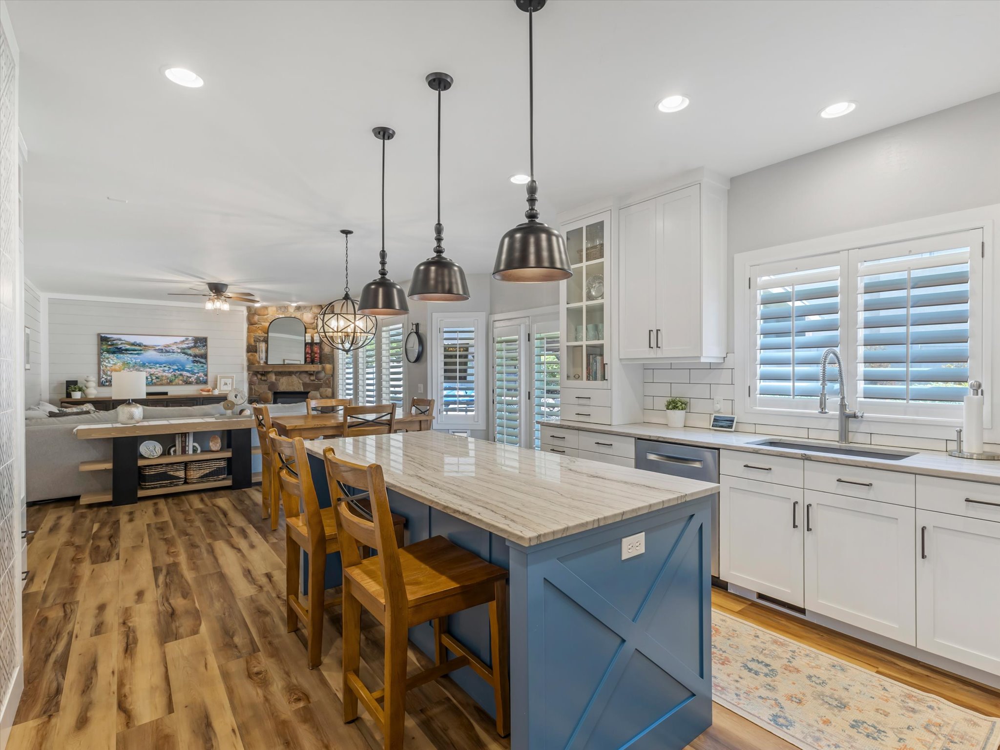 Kitchen featuring a large island with a substantial countertop, white cabinetry with dark hardware, subway tile backsplash, and wood-finish flooring
