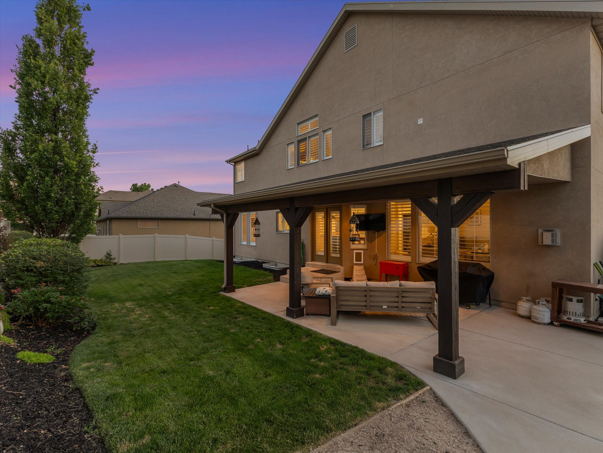 Covered outdoor patio with a concrete surface, supported by dark wood-finish columns